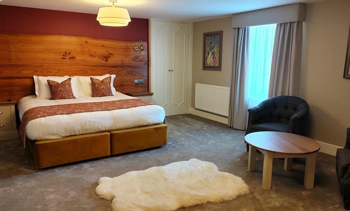 Extra large super king name inspired by Welsh Valentine. Spacious room with large extra large super king bed, armchairs and white furry rug.